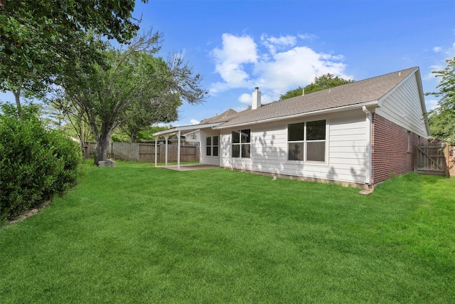 rear view of property with a lawn, a patio area, a fenced backyard, and a chimney