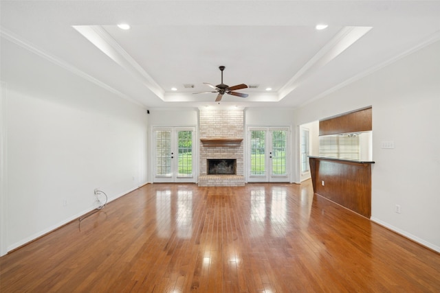 331 Moonshine Hill Rd, Houston, TX 77338 - unfurnished living room with crown molding, ceiling fan, wood-type flooring, a brick fireplace, and a raised ceiling