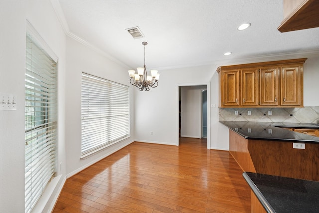 331 Moonshine Hill Rd, Houston, TX 77338 - kitchen featuring an inviting chandelier, brown cabinets, dark countertops, crown molding, and tasteful backsplash
