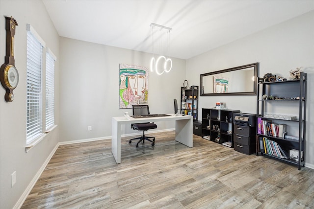 home office featuring a healthy amount of sunlight, baseboards, and light wood-style floors