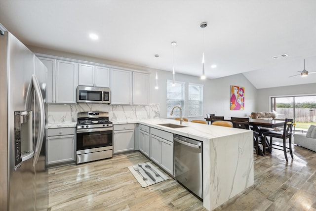 kitchen featuring gray cabinetry, open floor plan, stainless steel appliances, and a sink