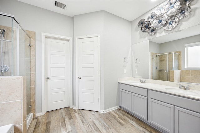 bathroom with wood finished floors, visible vents, a stall shower, and a sink