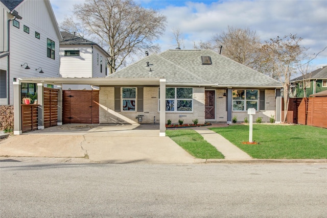 view of front of house with a front yard, a carport, brick siding, roof with shingles, and fence