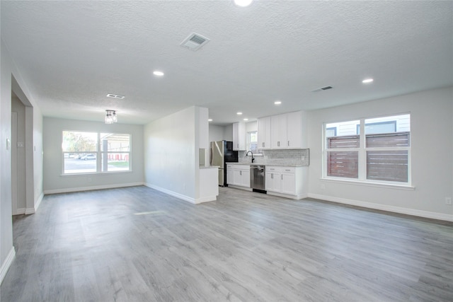 unfurnished living room featuring light wood-type flooring, visible vents, and baseboards
