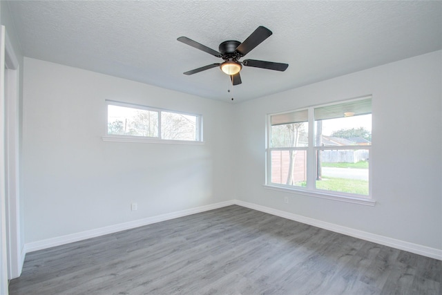 unfurnished room featuring wood finished floors, plenty of natural light, and baseboards