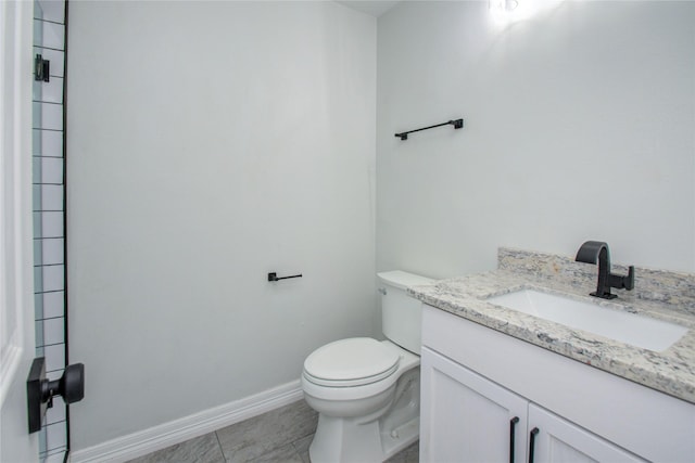 bathroom featuring toilet, tile patterned floors, vanity, and baseboards