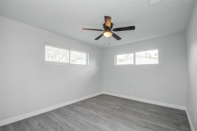 empty room featuring wood finished floors, visible vents, and baseboards
