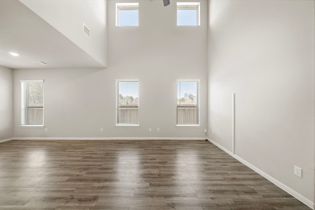 9993 Mountain Lion Ln, Magnolia, TX 77354 - unfurnished living room featuring dark wood-style flooring, visible vents, baseboards, and a high ceiling