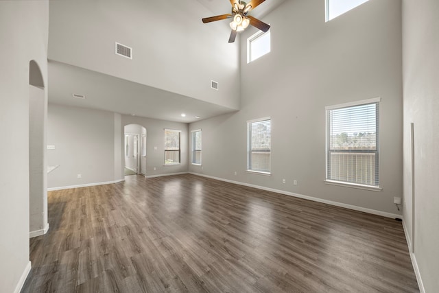 9993 Mountain Lion Ln, Magnolia, TX 77354 - unfurnished living room with arched walkways, wood finished floors, ceiling fan, baseboards, and visible vents