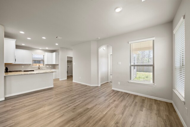 9993 Mountain Lion Ln, Magnolia, TX 77354 - unfurnished living room with recessed lighting, arched walkways, light wood-style flooring, and baseboards
