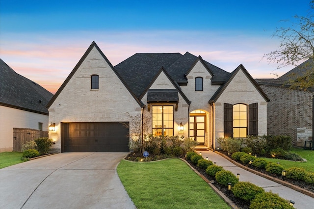 french country inspired facade featuring driveway, a front lawn, and brick siding