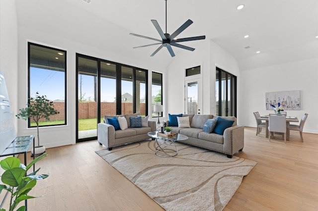 living area featuring baseboards, light wood-type flooring, recessed lighting, a ceiling fan, and high vaulted ceiling
