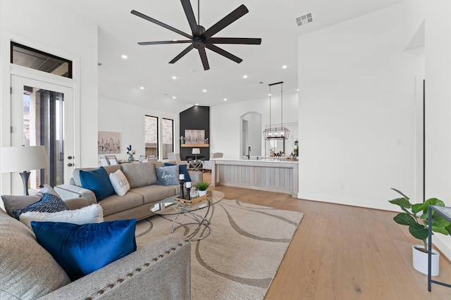 living area with visible vents, ceiling fan, light wood-style floors, arched walkways, and recessed lighting