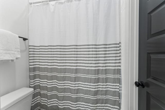 full bath featuring toilet and a shower with curtain