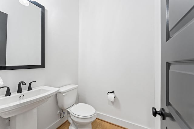 bathroom featuring a sink, wood finished floors, toilet, and baseboards