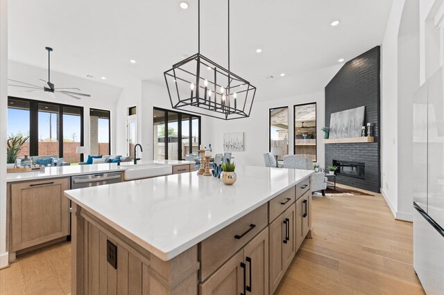 kitchen featuring a sink, a center island, open floor plan, recessed lighting, and a fireplace