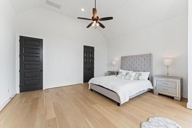 bedroom with visible vents, ceiling fan, baseboards, light wood finished floors, and high vaulted ceiling