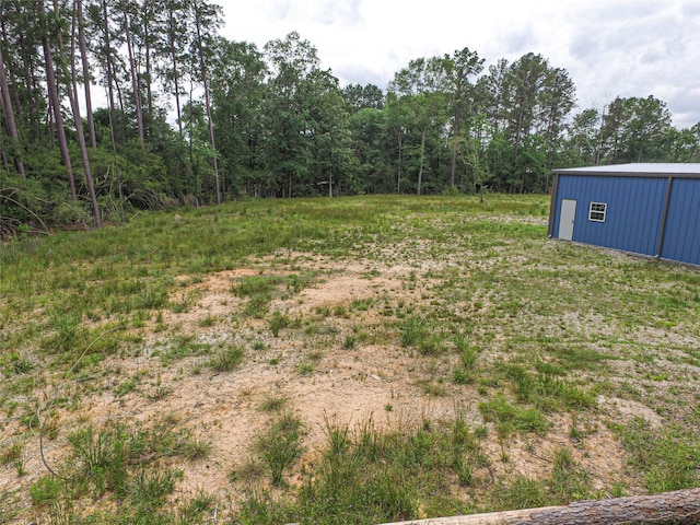 view of yard with a wooded view and an outbuilding
