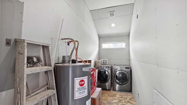 washroom with washing machine and clothes dryer, water heater, laundry area, and visible vents