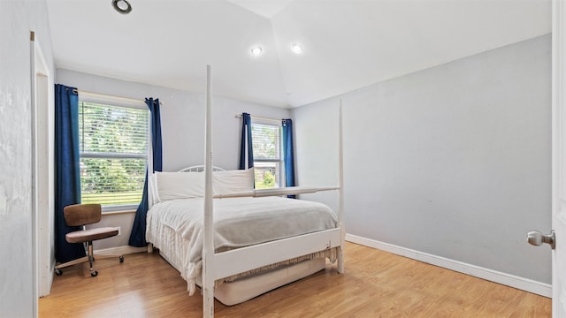 bedroom with baseboards, light wood finished floors, and vaulted ceiling