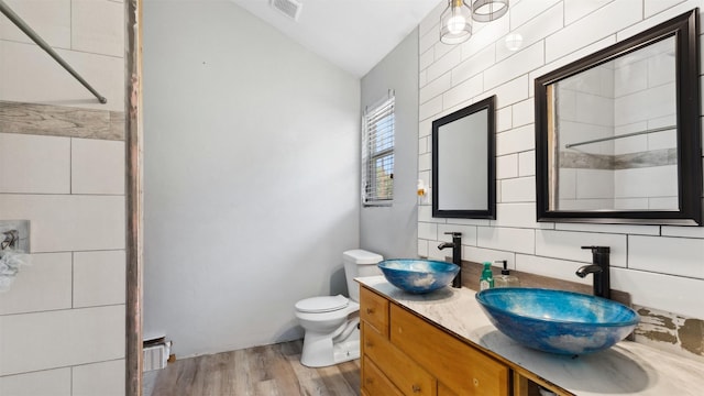bathroom featuring visible vents, wood finished floors, lofted ceiling, and a sink
