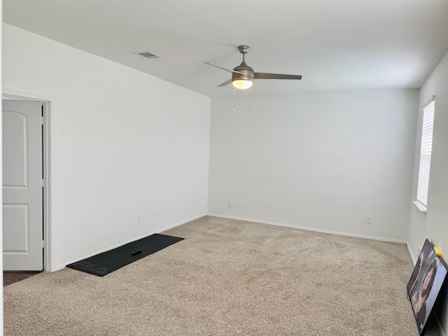 carpeted spare room with baseboards, ceiling fan, and visible vents