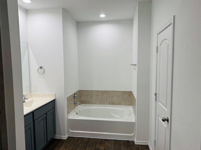 full bathroom with vanity, a garden tub, wood finished floors, and recessed lighting