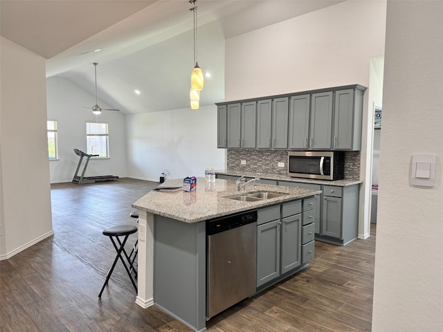 kitchen with appliances with stainless steel finishes, a sink, dark wood finished floors, decorative backsplash, and gray cabinetry