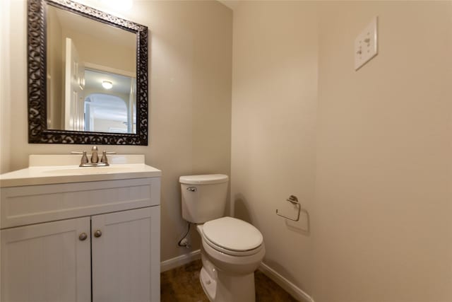 bathroom featuring baseboards, vanity, and toilet