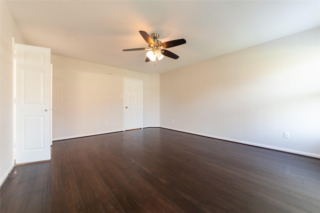 spare room with baseboards, a ceiling fan, and dark wood-type flooring