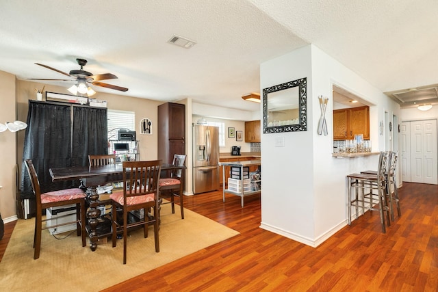 dining space featuring baseboards, visible vents, wood finished floors, and ceiling fan