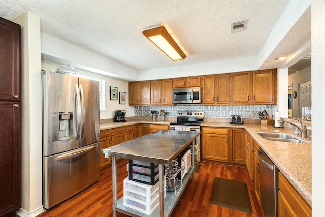 kitchen featuring a textured ceiling, a sink, appliances with stainless steel finishes, and visible vents