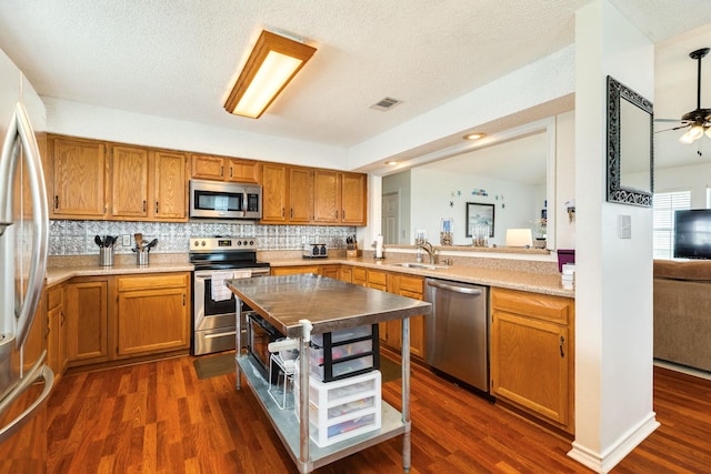 kitchen featuring appliances with stainless steel finishes, visible vents, brown cabinetry, and a sink