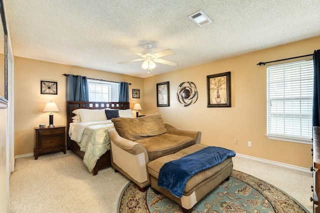 bedroom featuring a textured ceiling, visible vents, light colored carpet, and baseboards