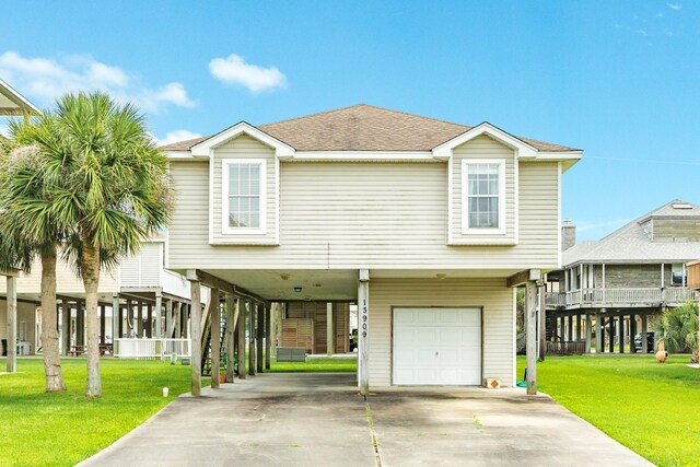 beach home featuring a front lawn, a carport, concrete driveway, and an attached garage