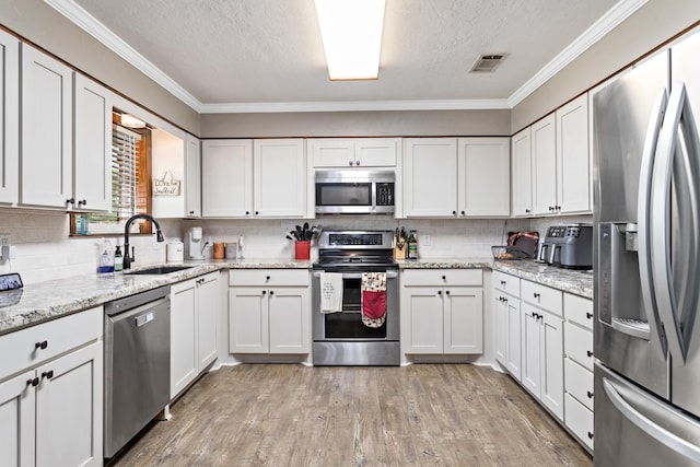 343 Pinemont Dr, Sour Lake, TX 77659 - kitchen featuring a textured ceiling, white cabinetry, a sink, stainless steel appliances, and light wood finished floors