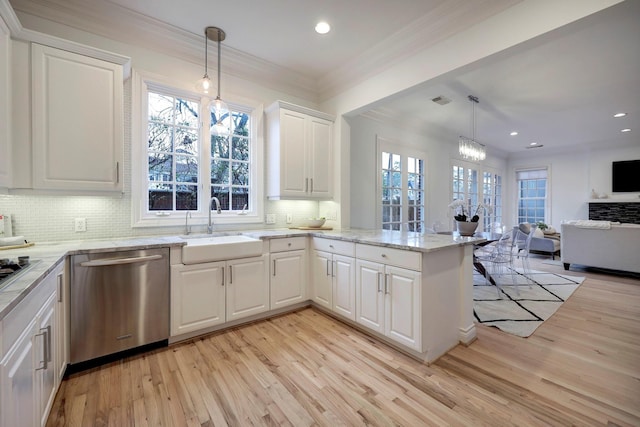 kitchen with a peninsula, open floor plan, light wood-type flooring, a sink, and appliances with stainless steel finishes