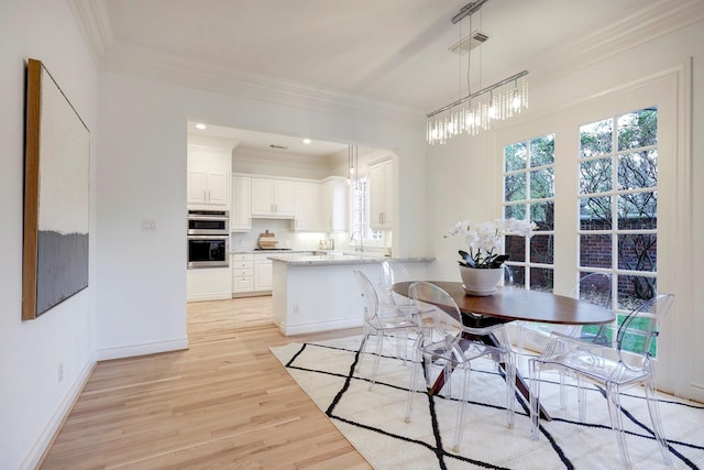 dining space with light wood-style floors, ornamental molding, baseboards, and visible vents