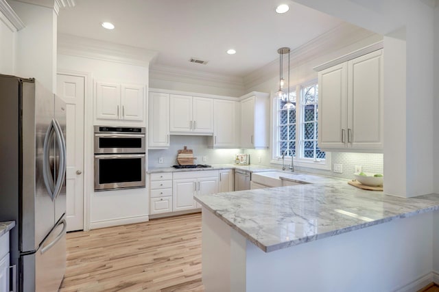 kitchen featuring a sink, a peninsula, white cabinets, and stainless steel appliances