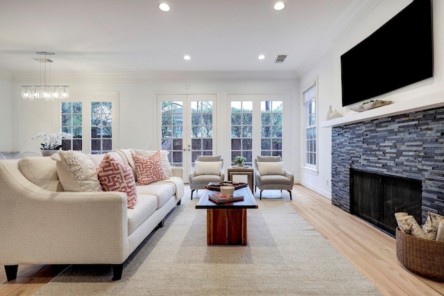 living room with a fireplace, light wood-type flooring, a chandelier, ornamental molding, and recessed lighting