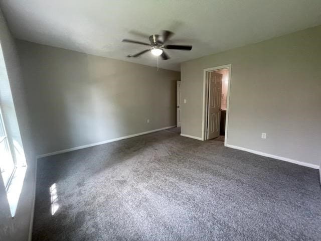 unfurnished room featuring a ceiling fan, dark colored carpet, and baseboards
