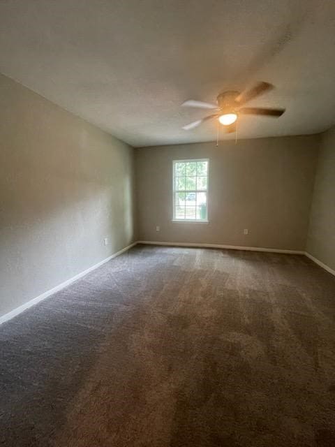 carpeted spare room with a ceiling fan and baseboards