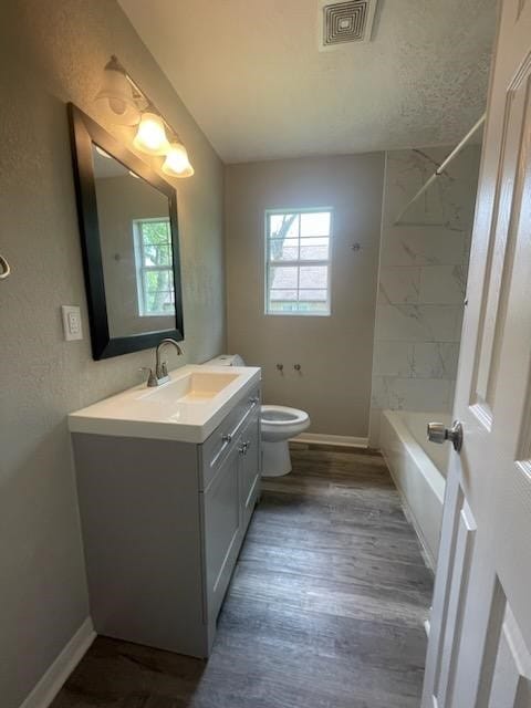 full bathroom featuring vanity, bathing tub / shower combination, toilet, visible vents, and wood finished floors