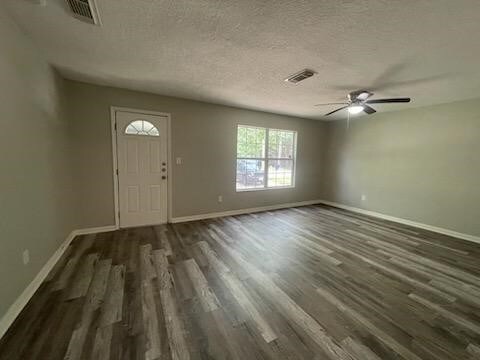 foyer entrance with a ceiling fan, visible vents, baseboards, a textured ceiling, and wood finished floors