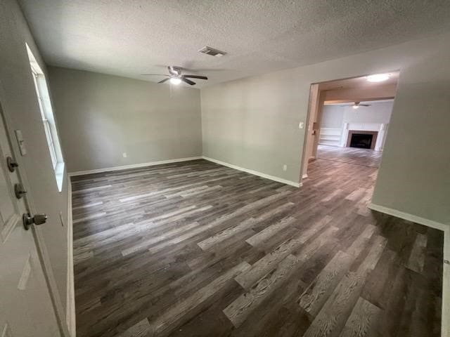 spare room with a textured ceiling, ceiling fan, baseboards, and dark wood-type flooring