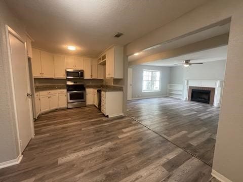 kitchen featuring dark wood-style floors, dark countertops, appliances with stainless steel finishes, and baseboards