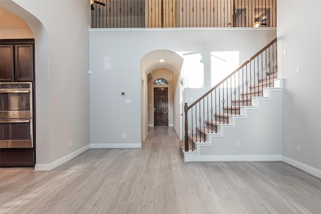 3302 Indigo Acres Ct, Katy, TX 77494 - foyer featuring arched walkways, stairs, light wood-style floors, baseboards, and a towering ceiling