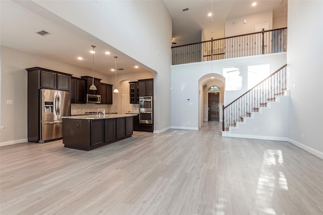3302 Indigo Acres Ct, Katy, TX 77494 - kitchen featuring a kitchen island with sink, stainless steel appliances, dark brown cabinetry, arched walkways, and open floor plan