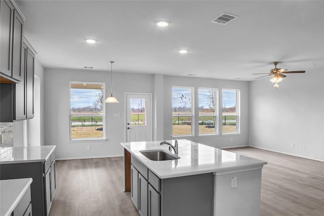 kitchen with visible vents, light countertops, light wood-style flooring, and a sink