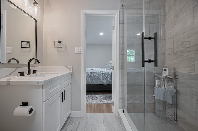 ensuite bathroom featuring connected bathroom, vanity, a shower stall, and baseboards
